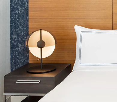 a lamp on a nightstand next to a bed