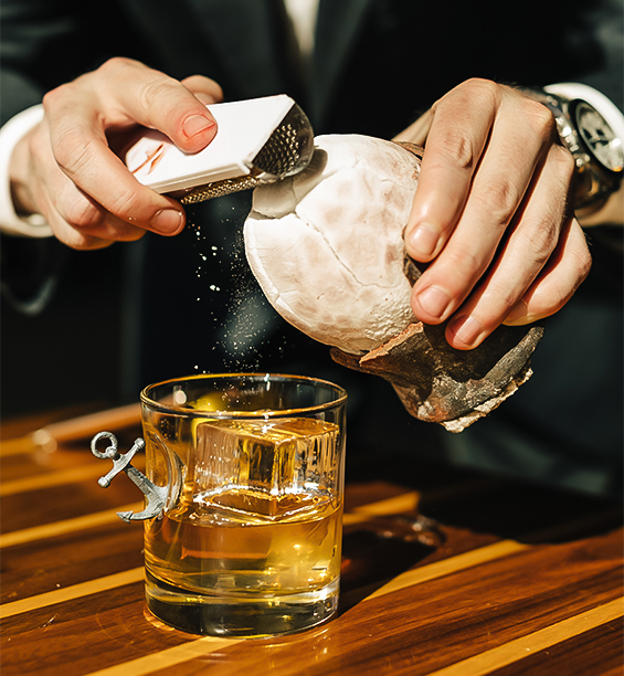 a person squeezing a coconut into a glass of liquid