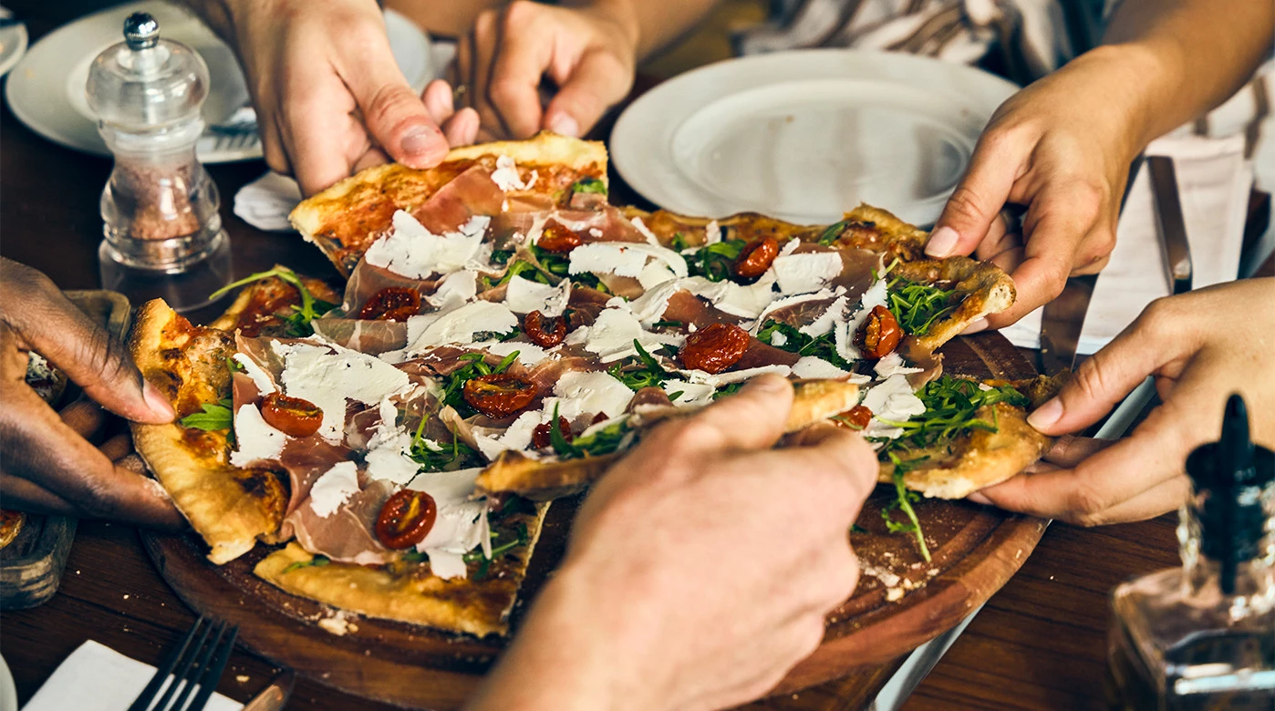 a group of people holding pizzas