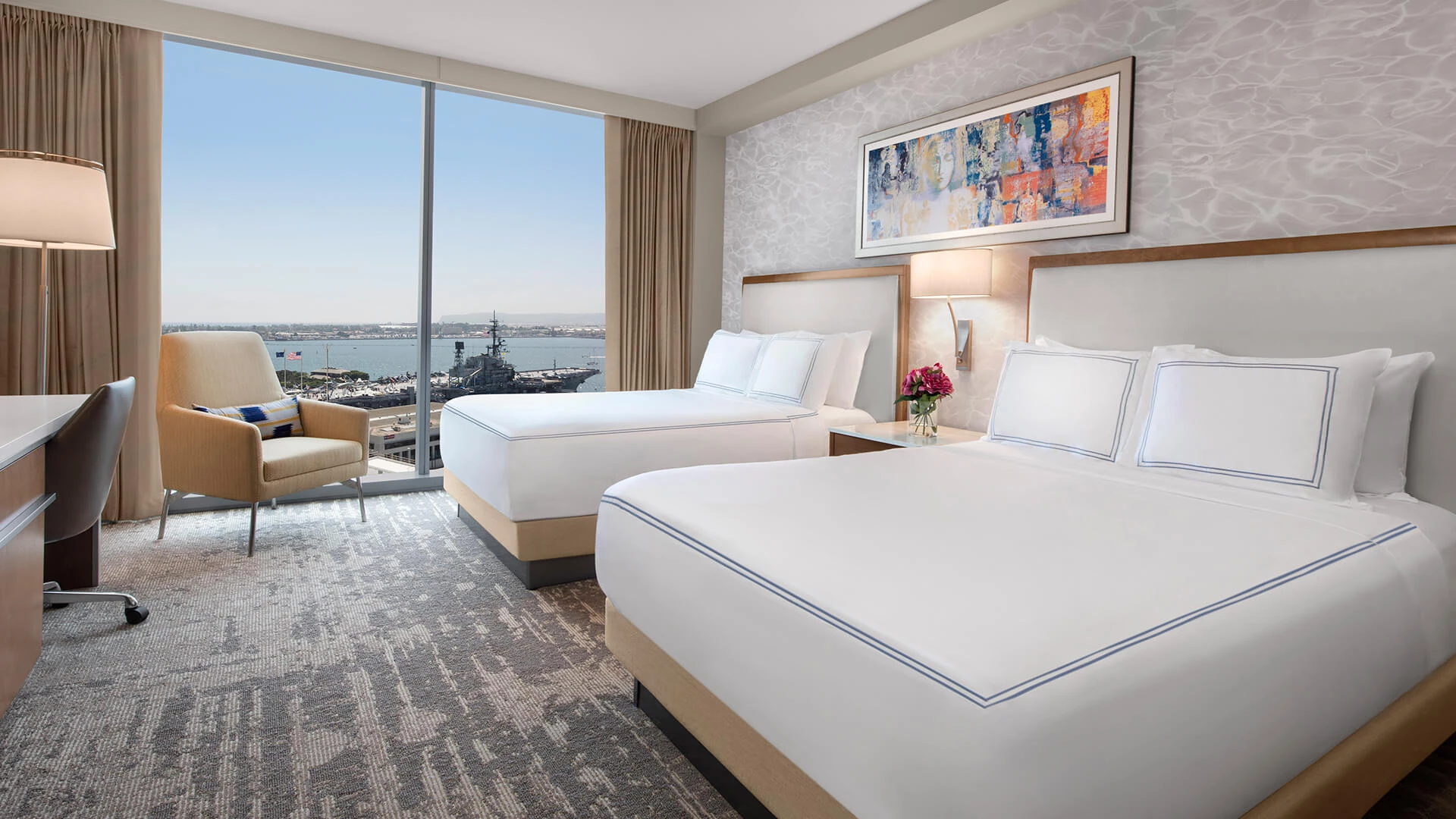 a room with two beds and a view of the water