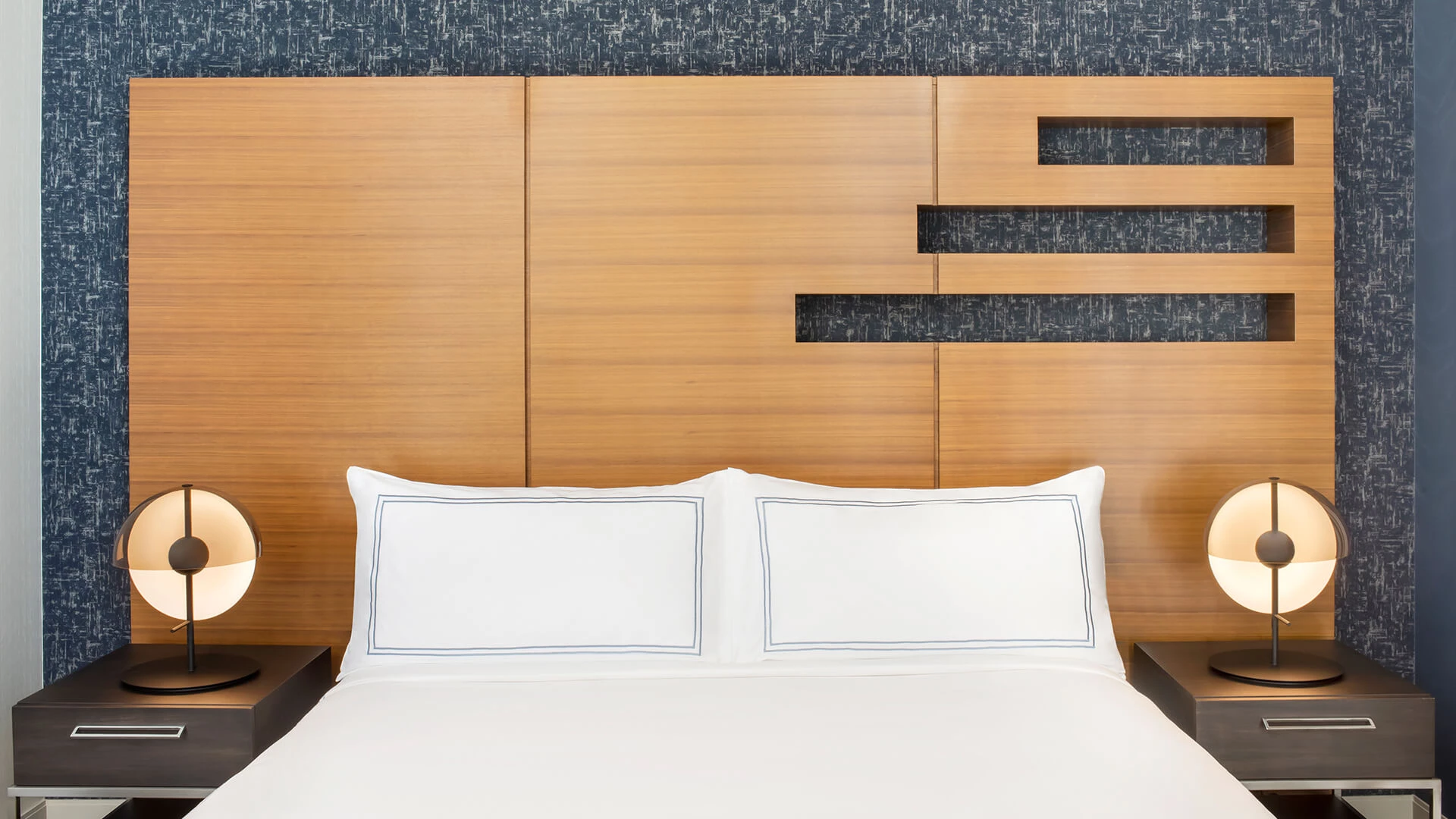 a bed with white pillows and a wood headboard