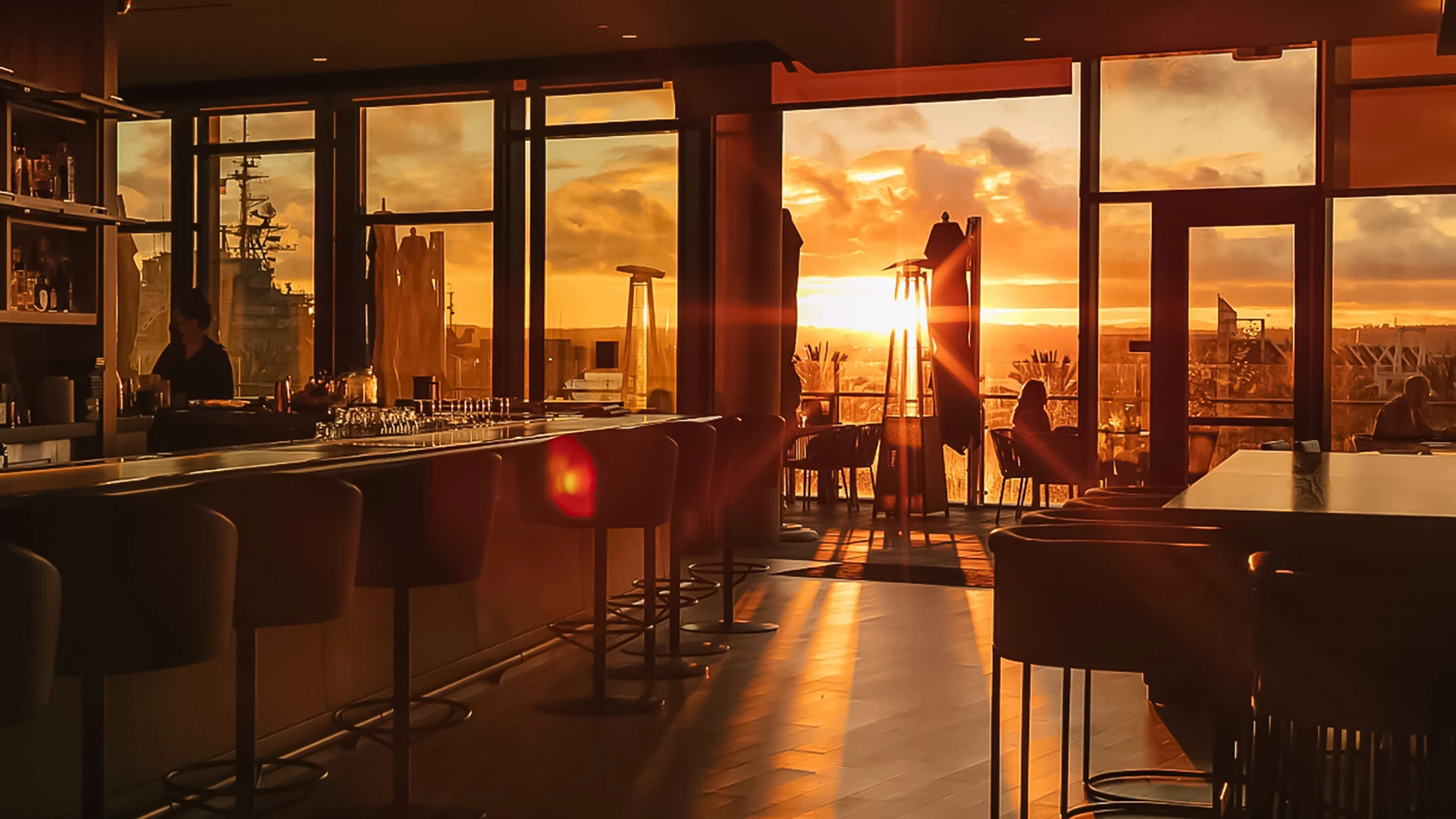 a room with a bar and chairs and a sunset