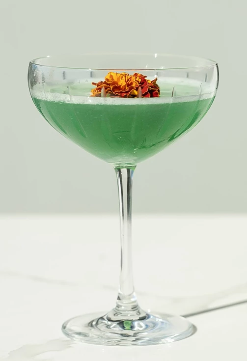 a glass with a green liquid and a flower in it