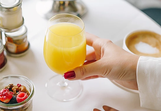 a hand holding a glass of orange juice
