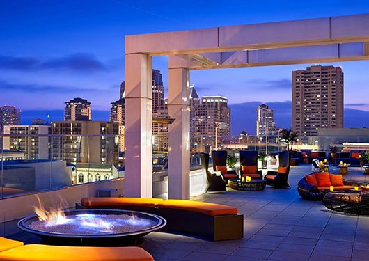 a rooftop patio with a fire pit and chairs