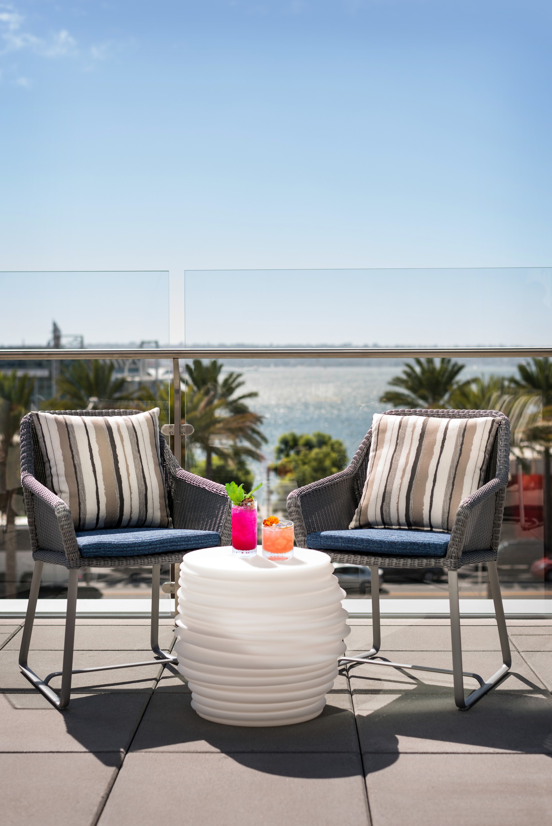 a table with drinks on it and chairs on a balcony