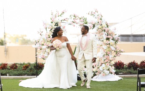 a man and woman in white wedding attire holding hands and walking