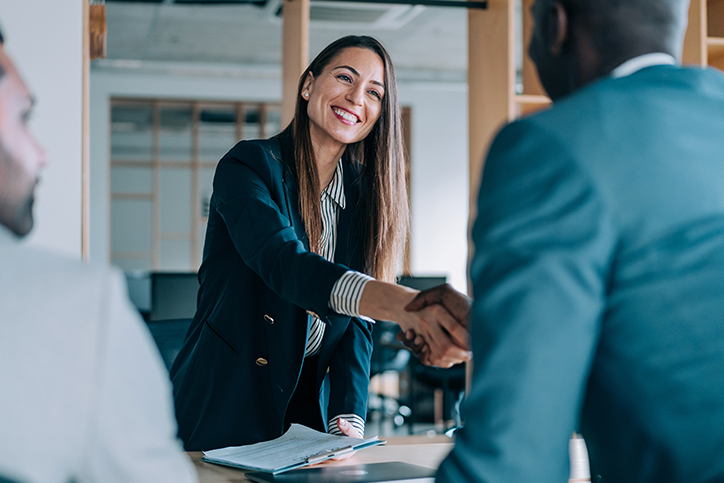 a woman in a suit shaking hands with a man in a suit