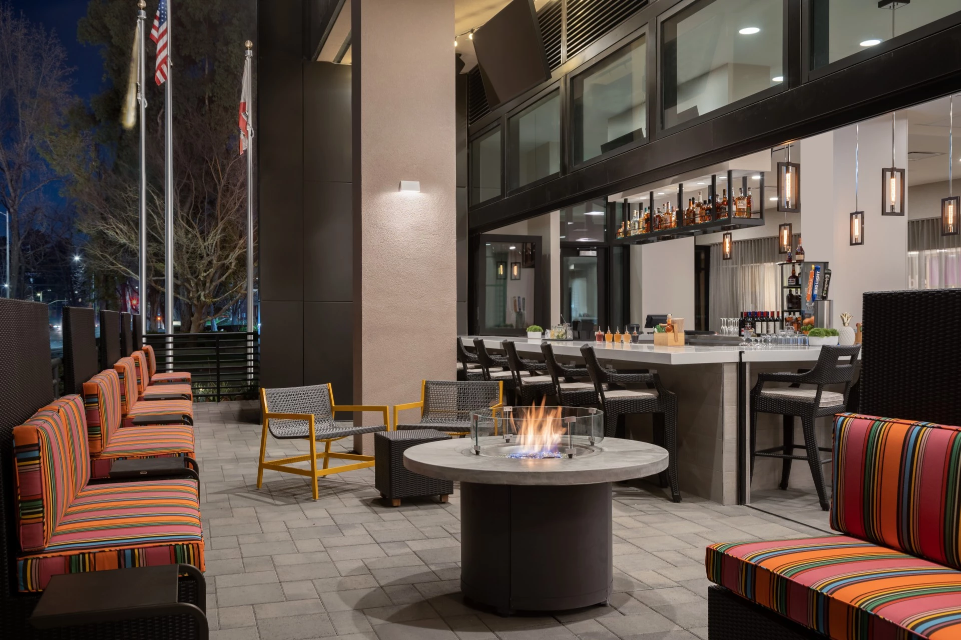 a fire pit with chairs and a bar with flags