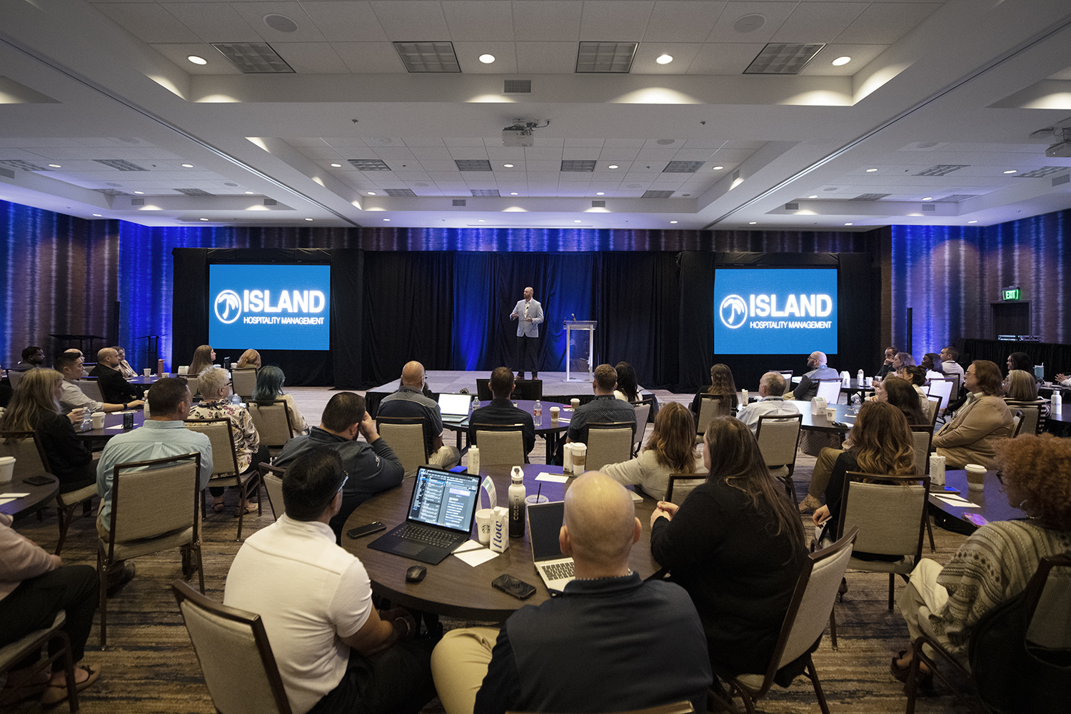a man standing in front of a group of people seated at tables