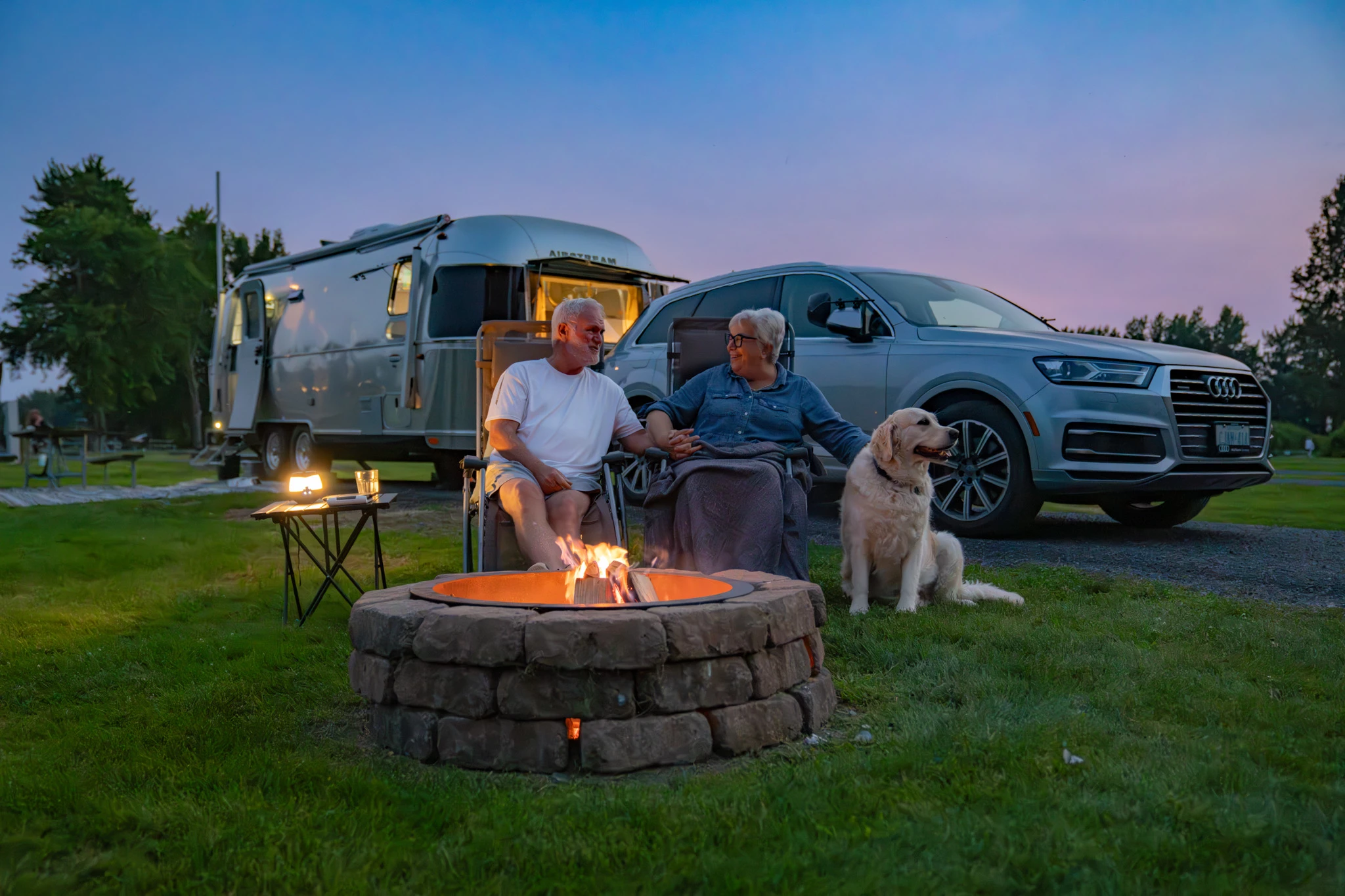 a man and woman sitting in front of a campfire