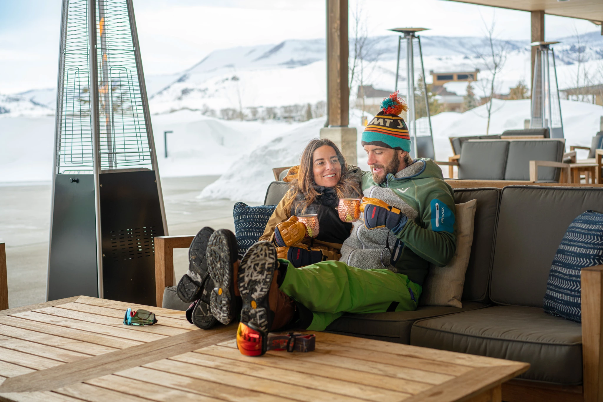a man and woman sitting on a couch with cups on it