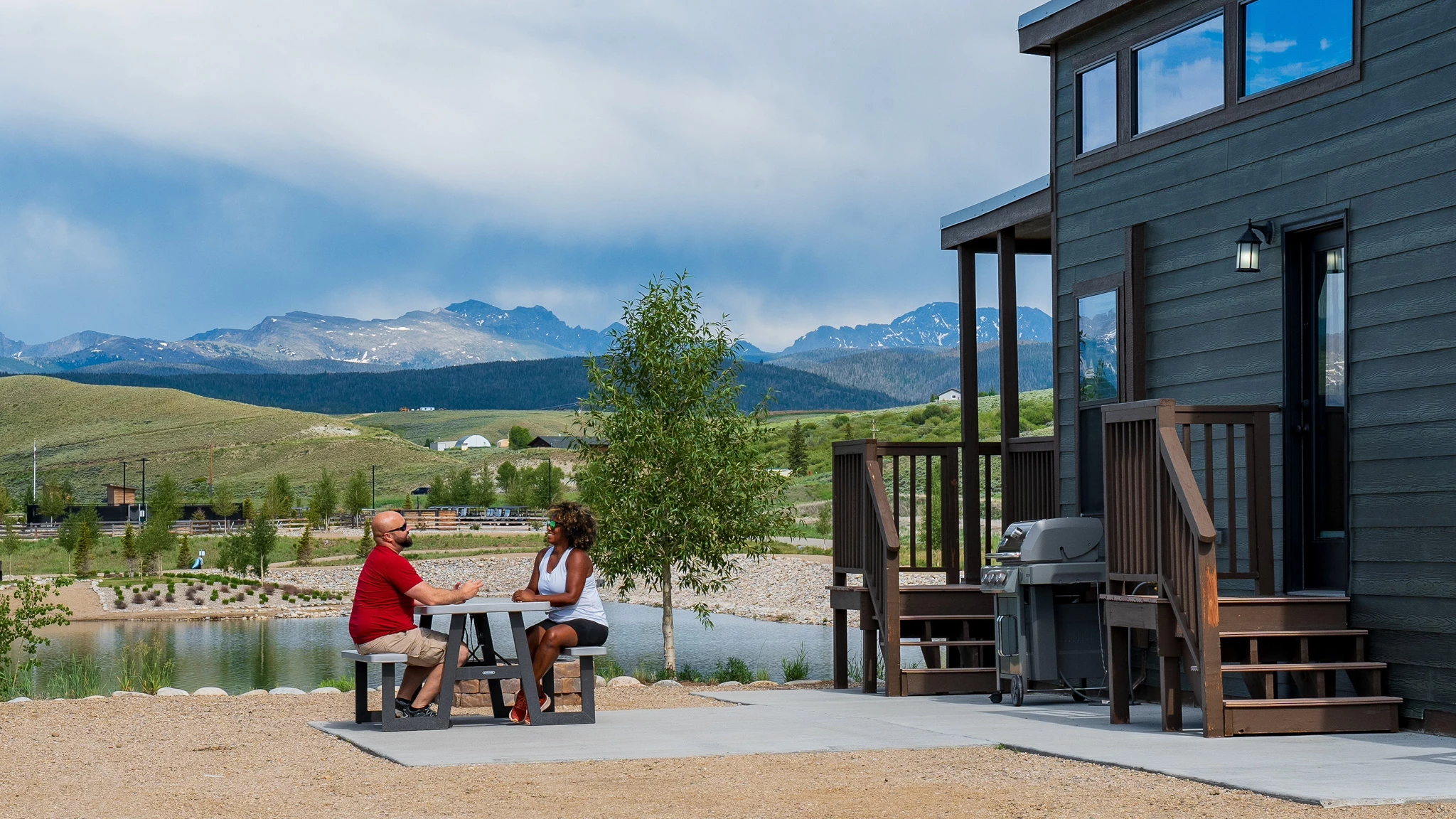 a man and woman sitting at a table outside a house