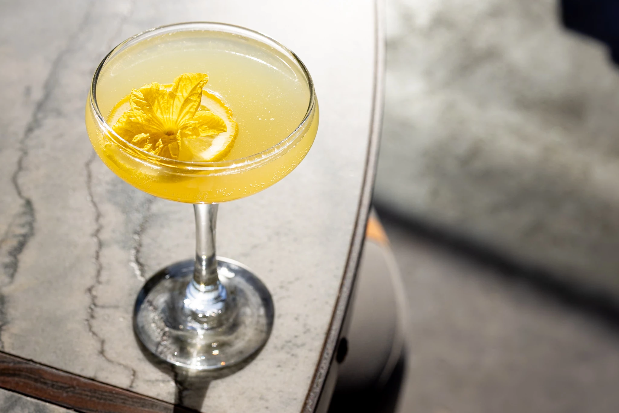 a glass with a drink and a slice of lemon on top of it