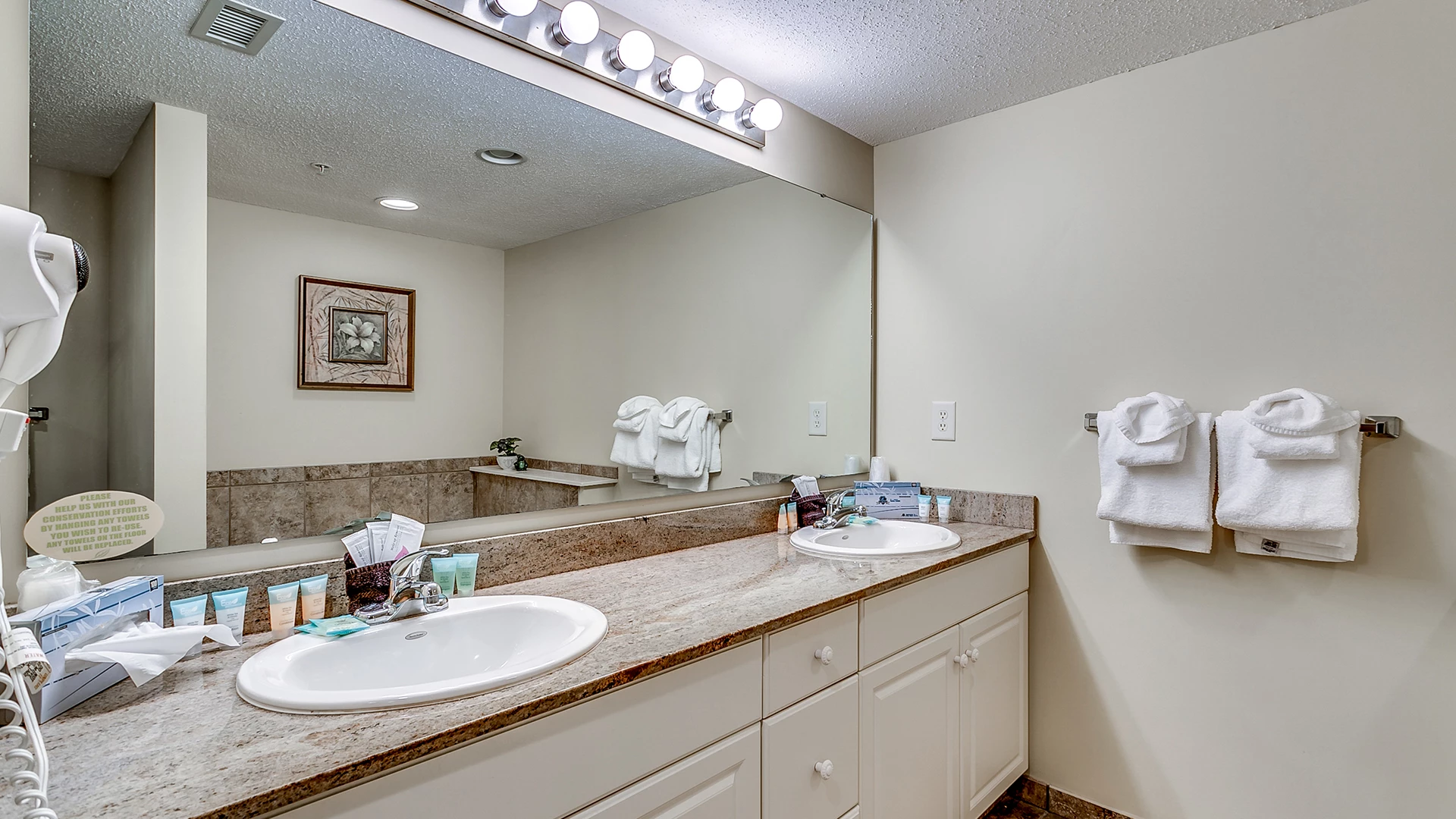 A clean bathroom with a double vanity, granite countertops, and a large mirror.