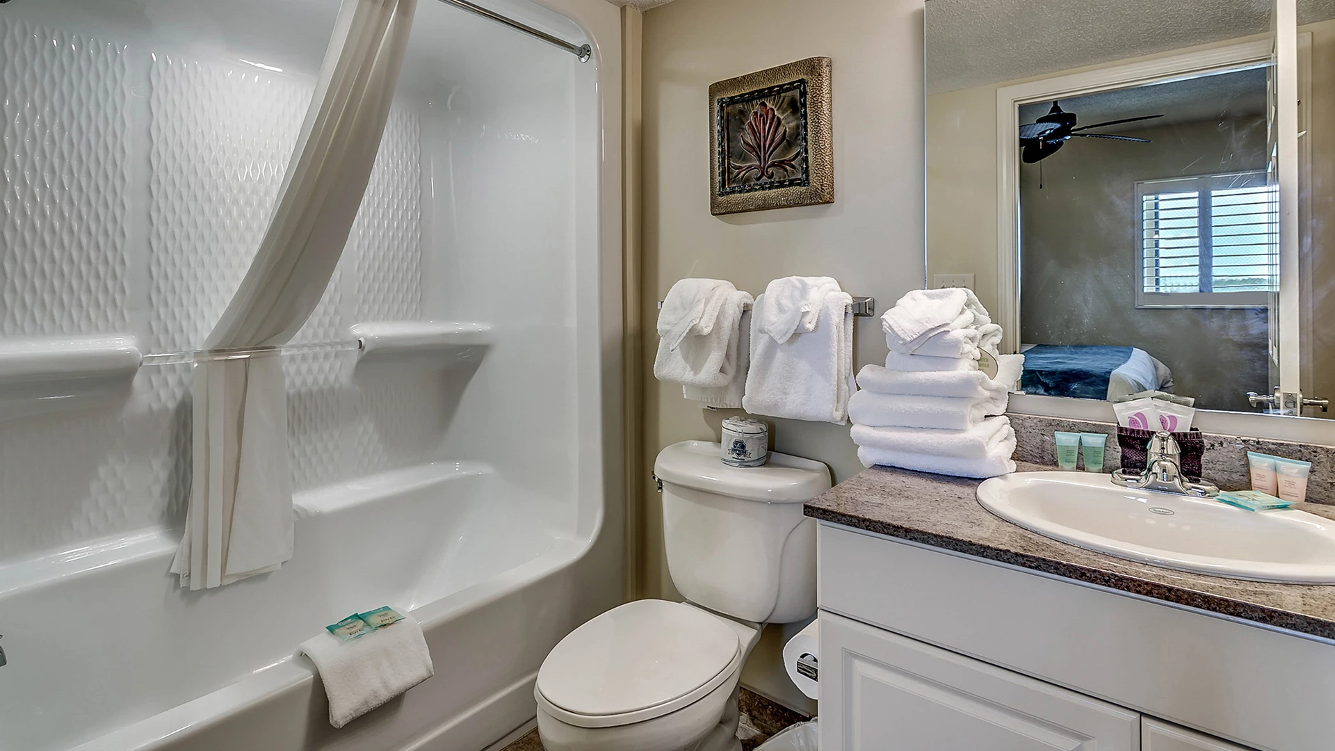 A clean bathroom with a bathtub, toilet, sink, and towels.