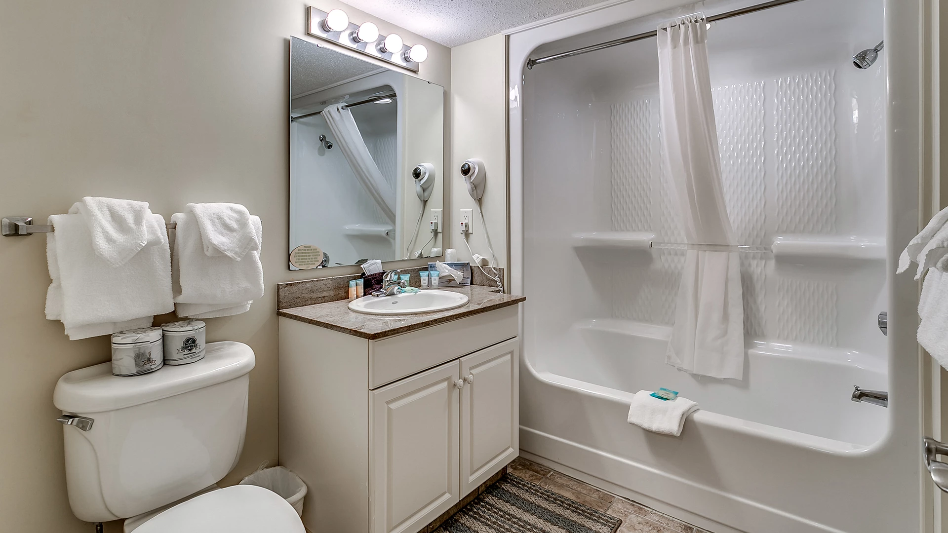 A bathroom with a toilet, sink, bathtub, and mirror.