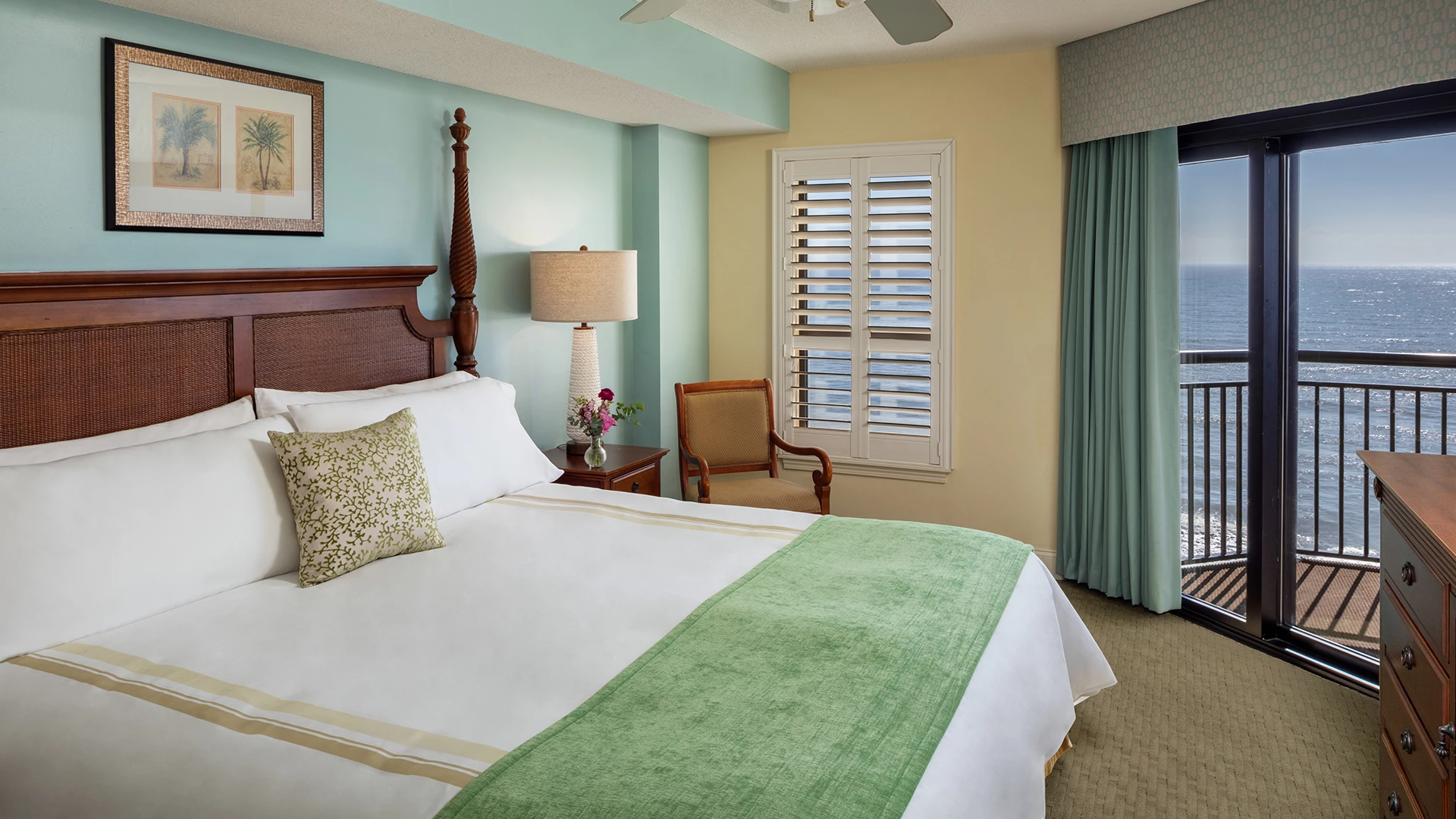 A hotel room with a large bed, balcony, and ocean view.