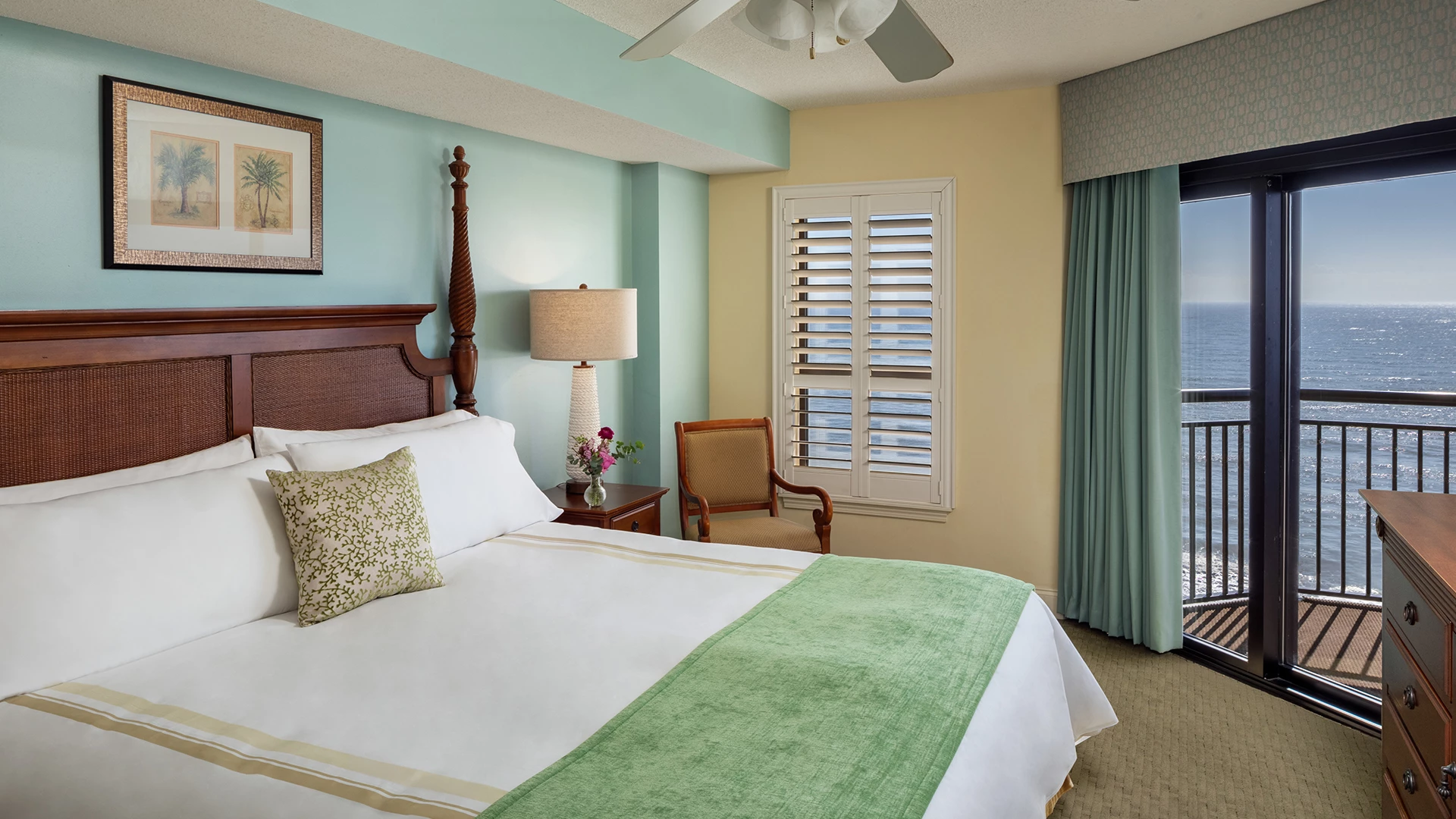 A wide-angle view of a guest room with a large bed, balcony access, and an ocean view.