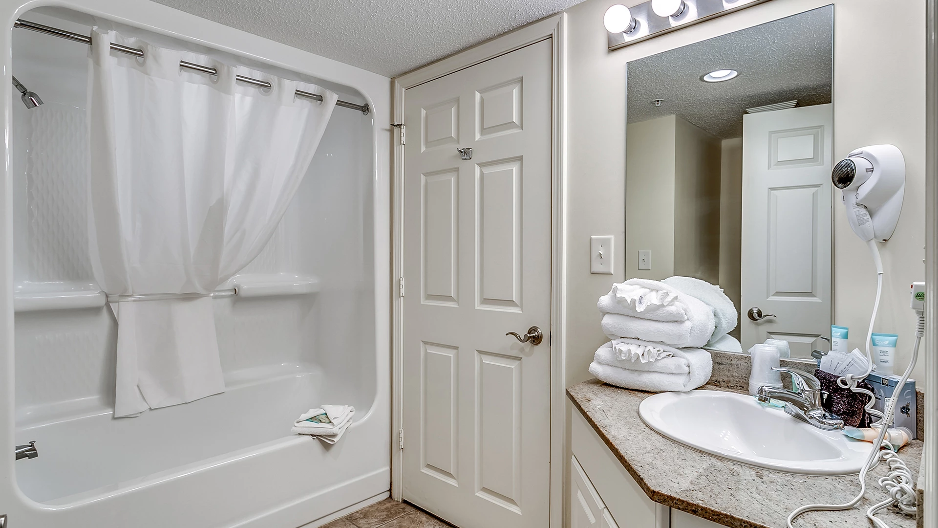 A clean bathroom with a shower, sink, and towels.