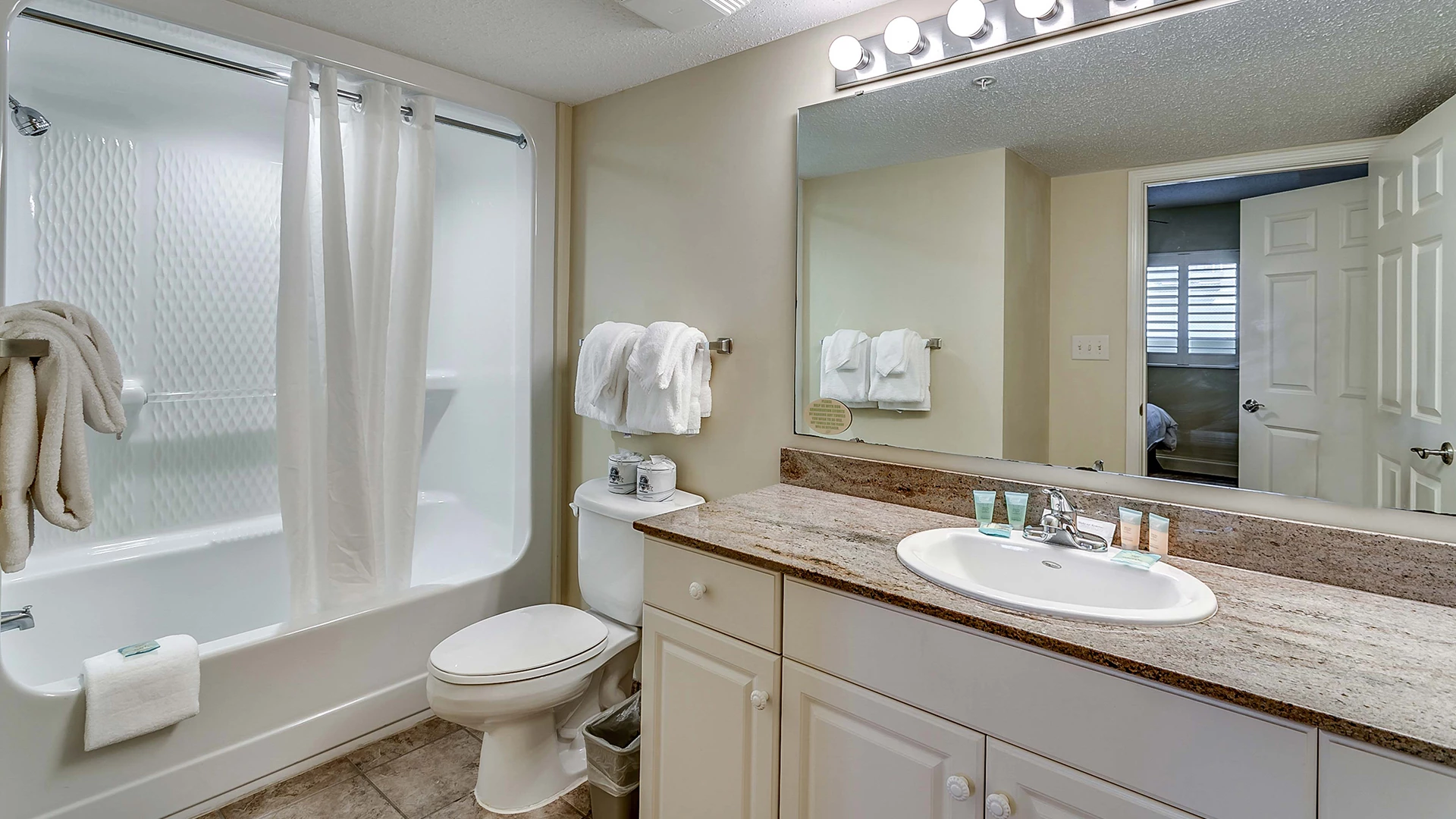 A clean and well-lit bathroom with a bathtub, toilet, and sink.