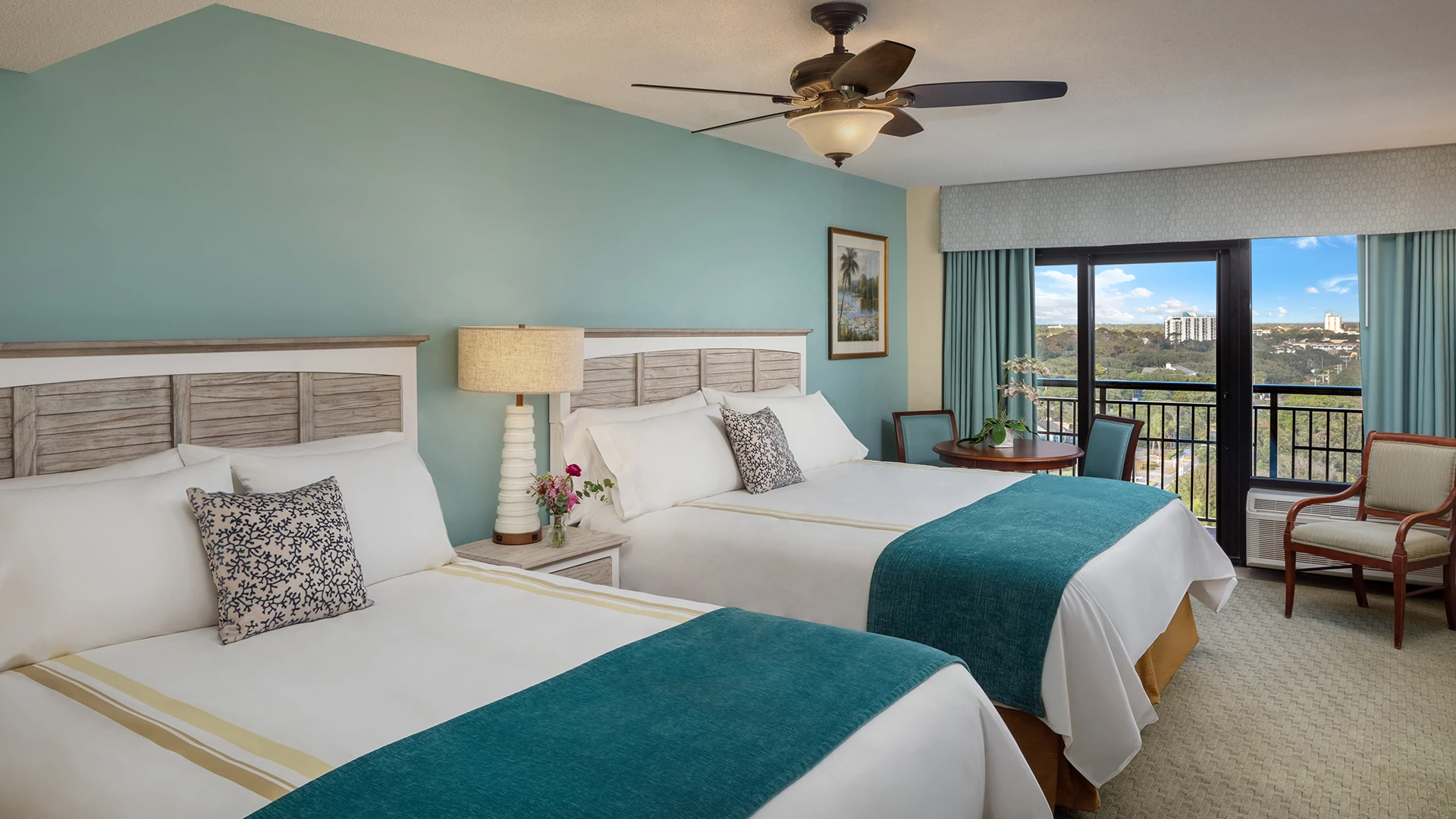 A hotel room with two beds, a balcony, and a view.