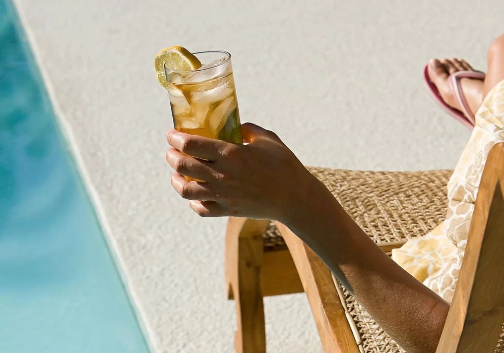 a person holding a glass of ice tea