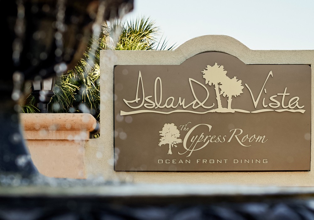 a sign with a palm tree in the background