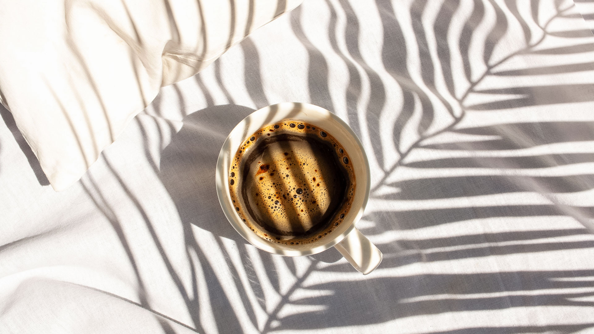 a cup of coffee with shadows on a white surface