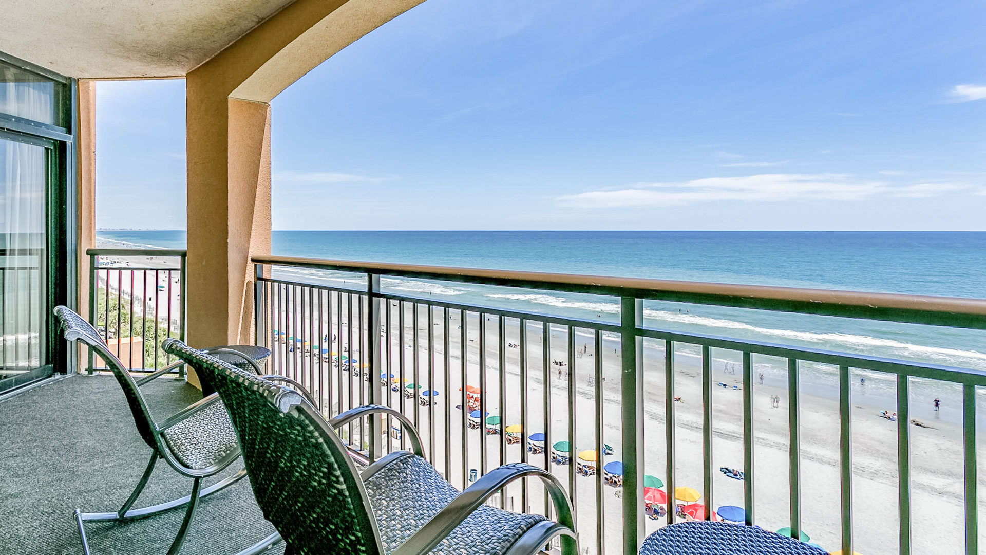a balcony with chairs and a beach view