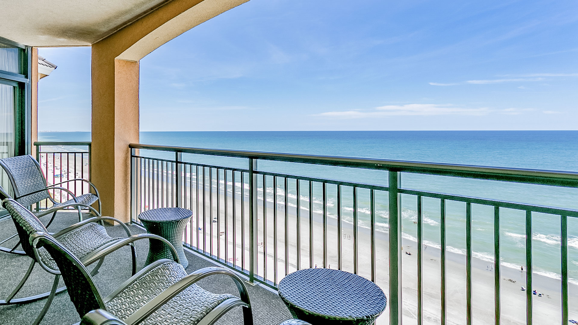 a balcony with chairs and table and a beach view