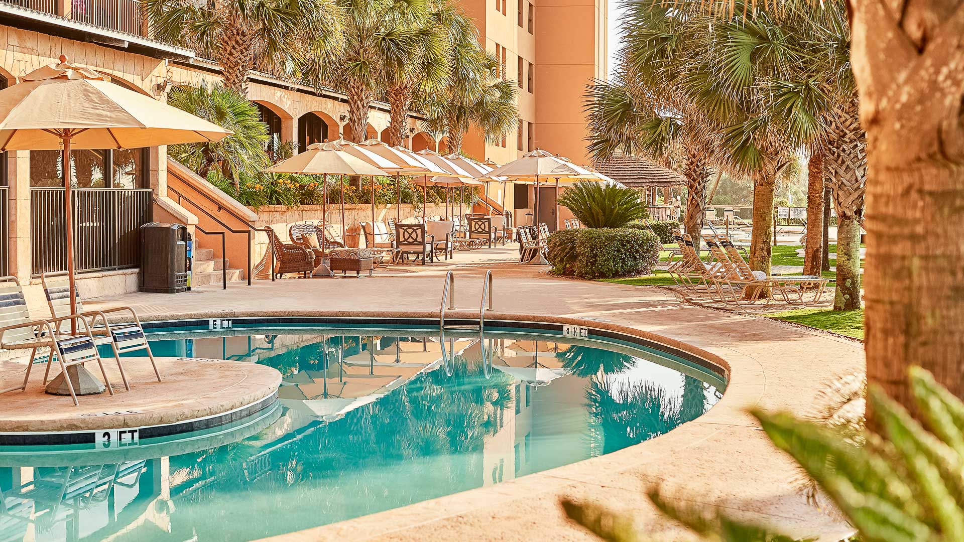 a pool with umbrellas and chairs in front of a building