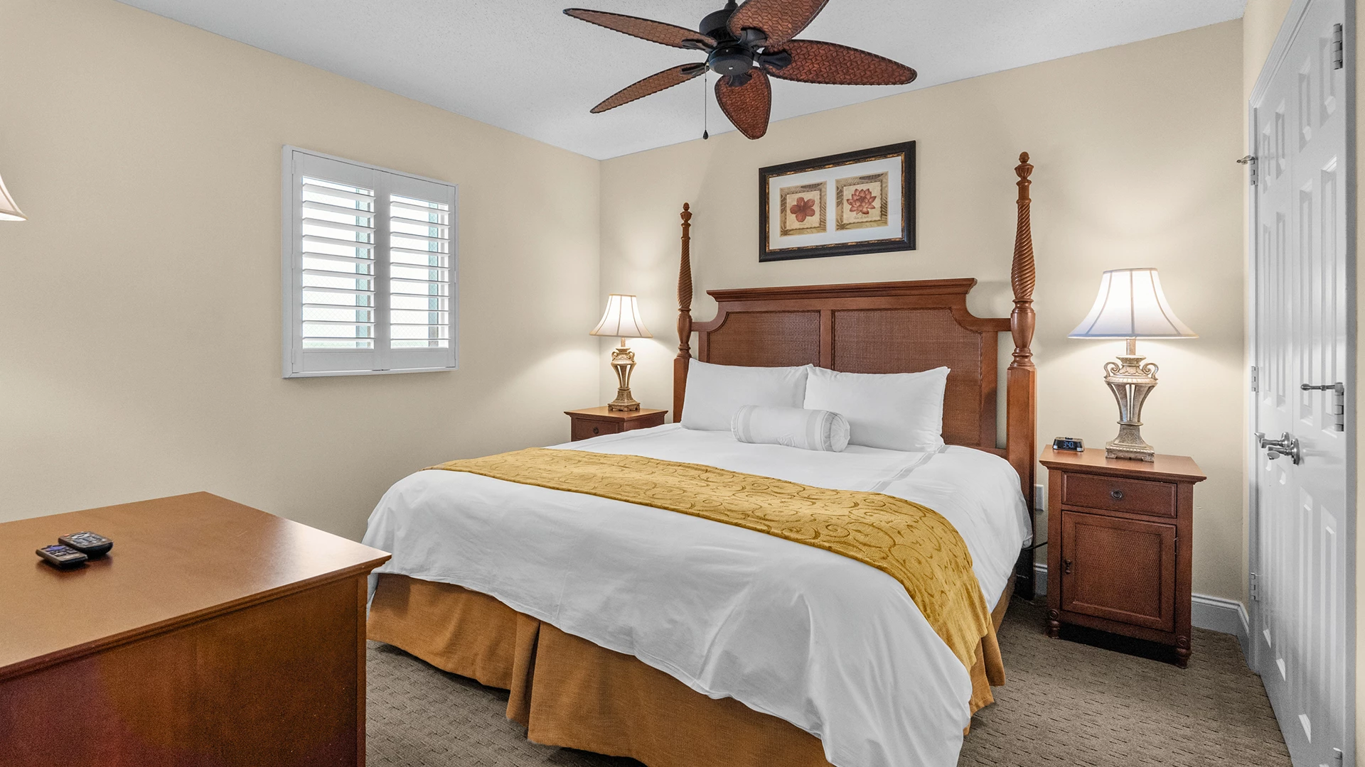 A hotel room with a bed, nightstands, lamps, and a desk.