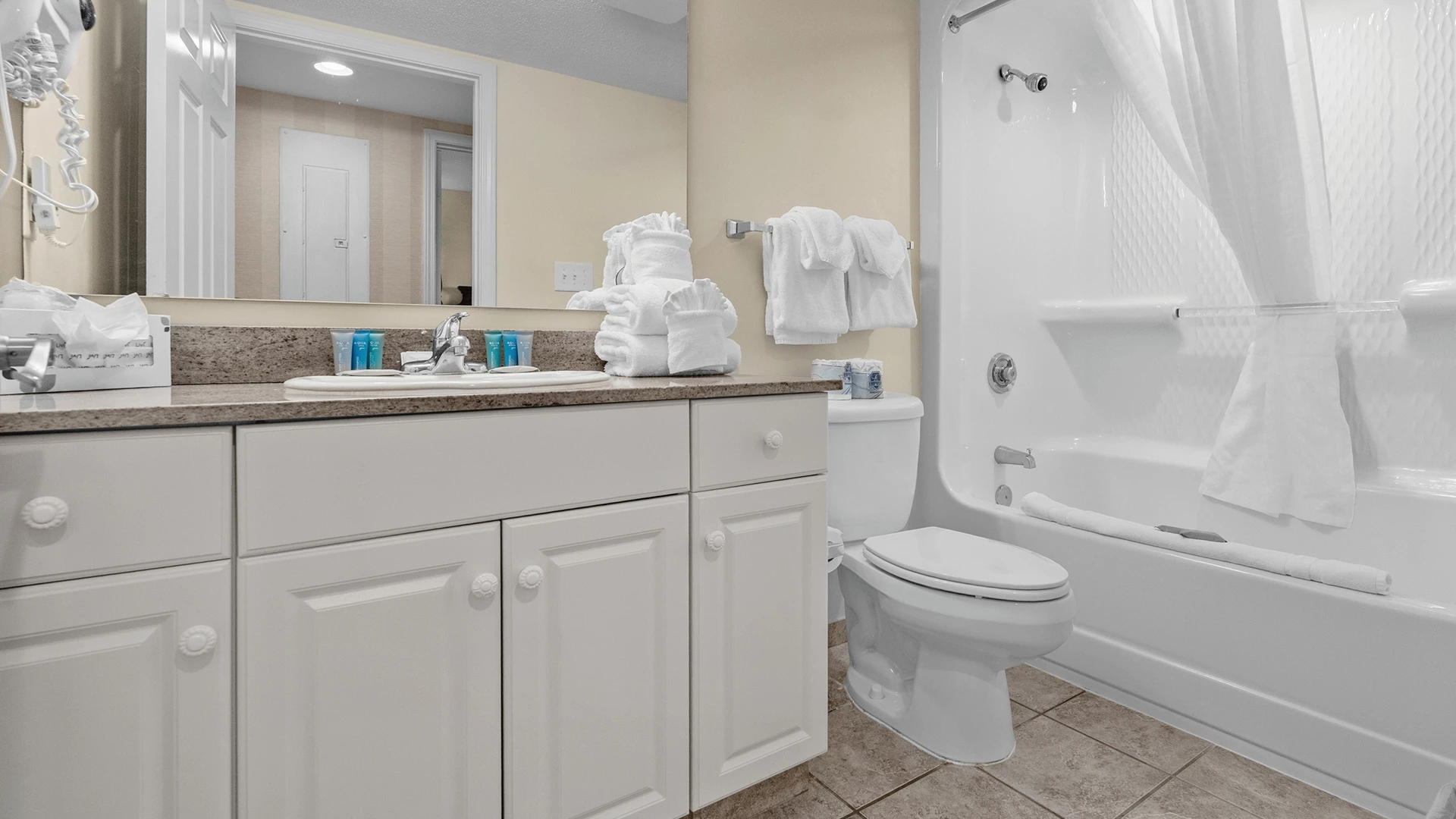 A clean bathroom with a sink, toilet, bathtub, and mirror