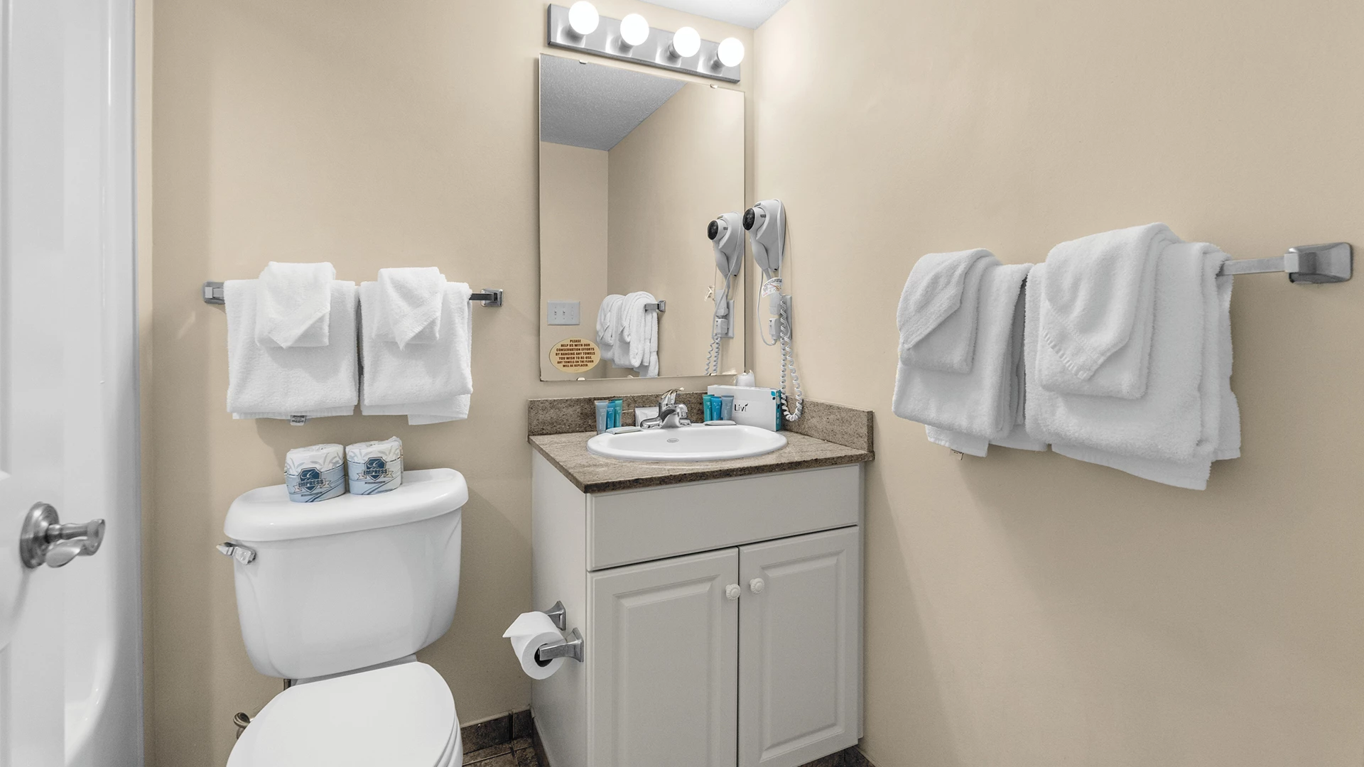A standard hotel bathroom with a toilet, sink, and towels