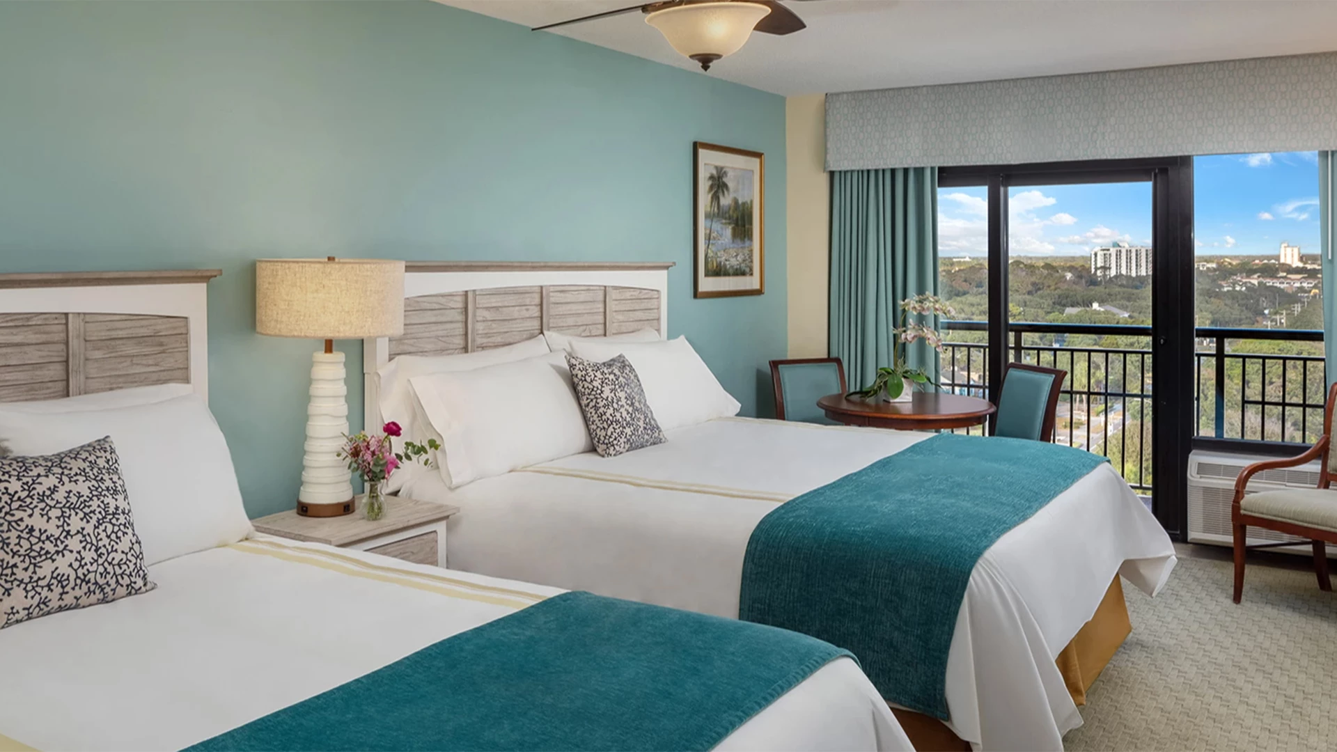 A hotel room with two beds, a balcony, and a view.