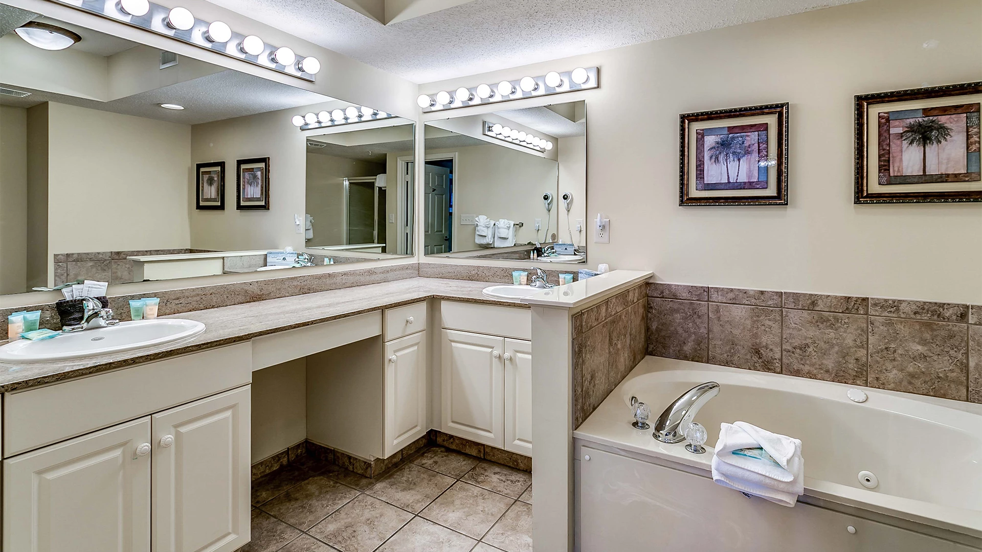 A clean and well-lit bathroom with a double vanity, jacuzzi tub, and large mirror.