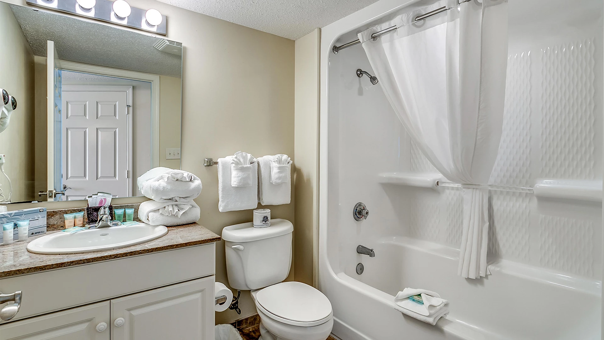 A clean bathroom with a toilet, sink, bathtub, and towels.