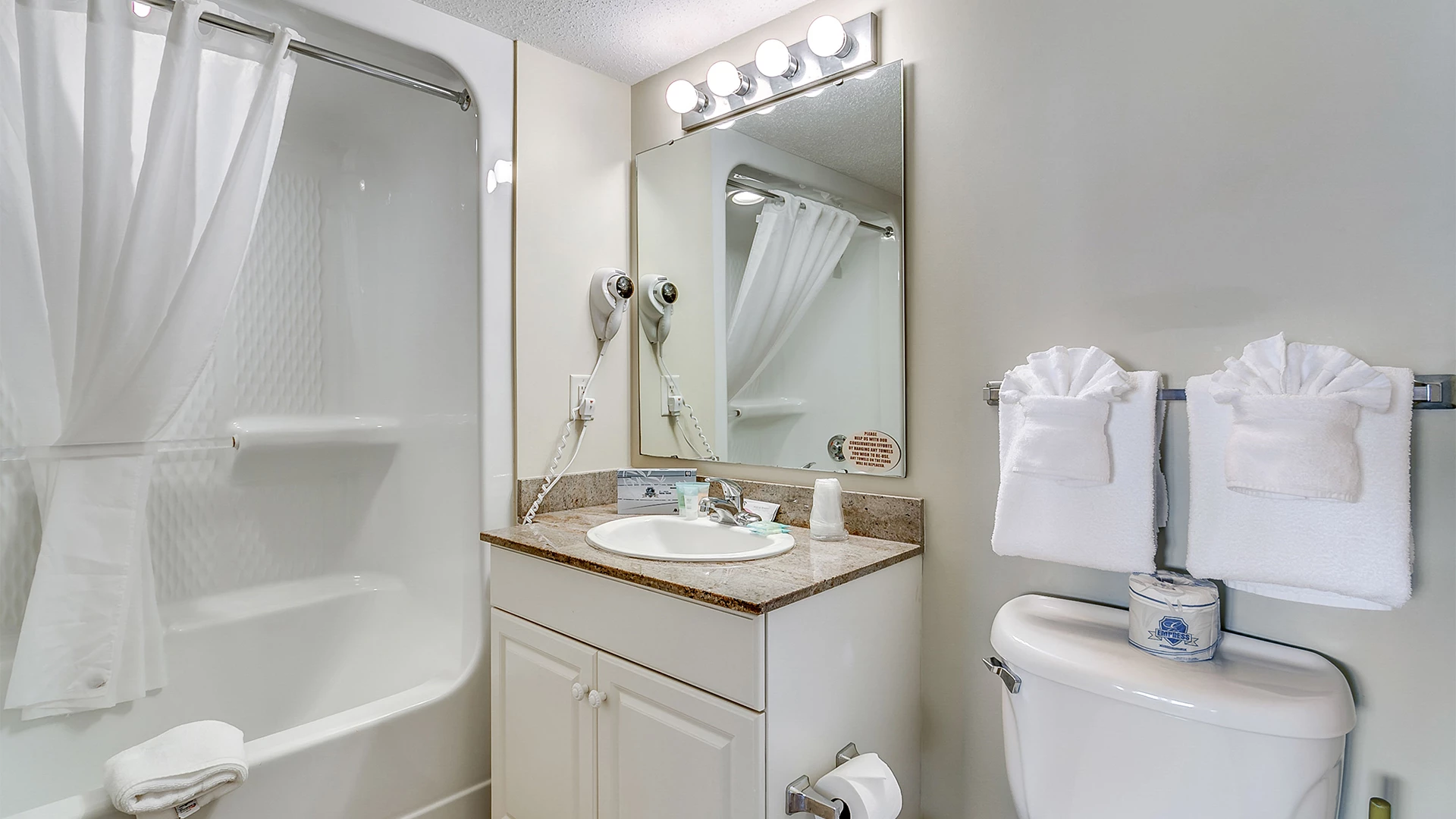 A clean bathroom with a bathtub, sink, toilet, and towels