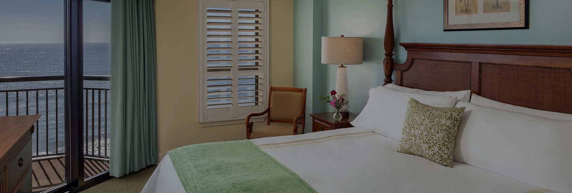 A guest room with a large bed, balcony, and ocean view.