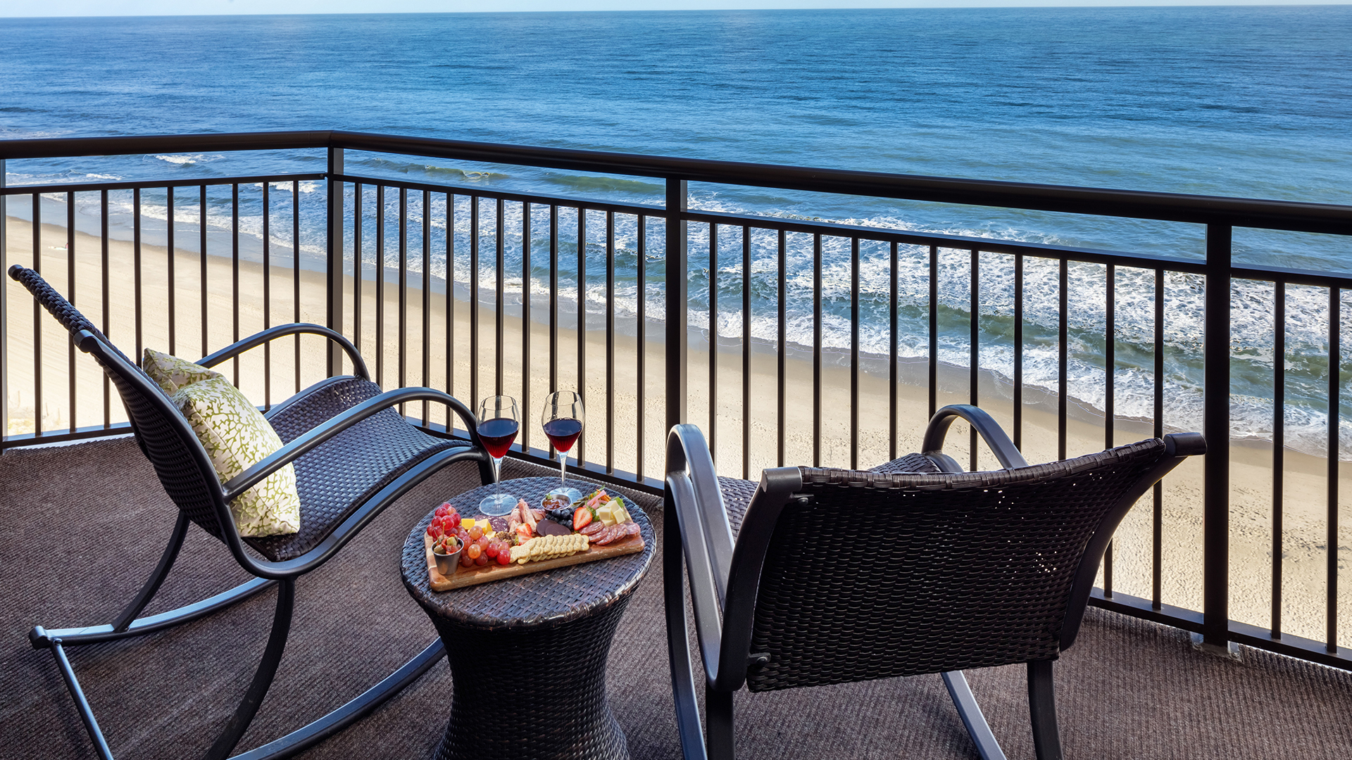 a table and chairs on a balcony overlooking the ocean