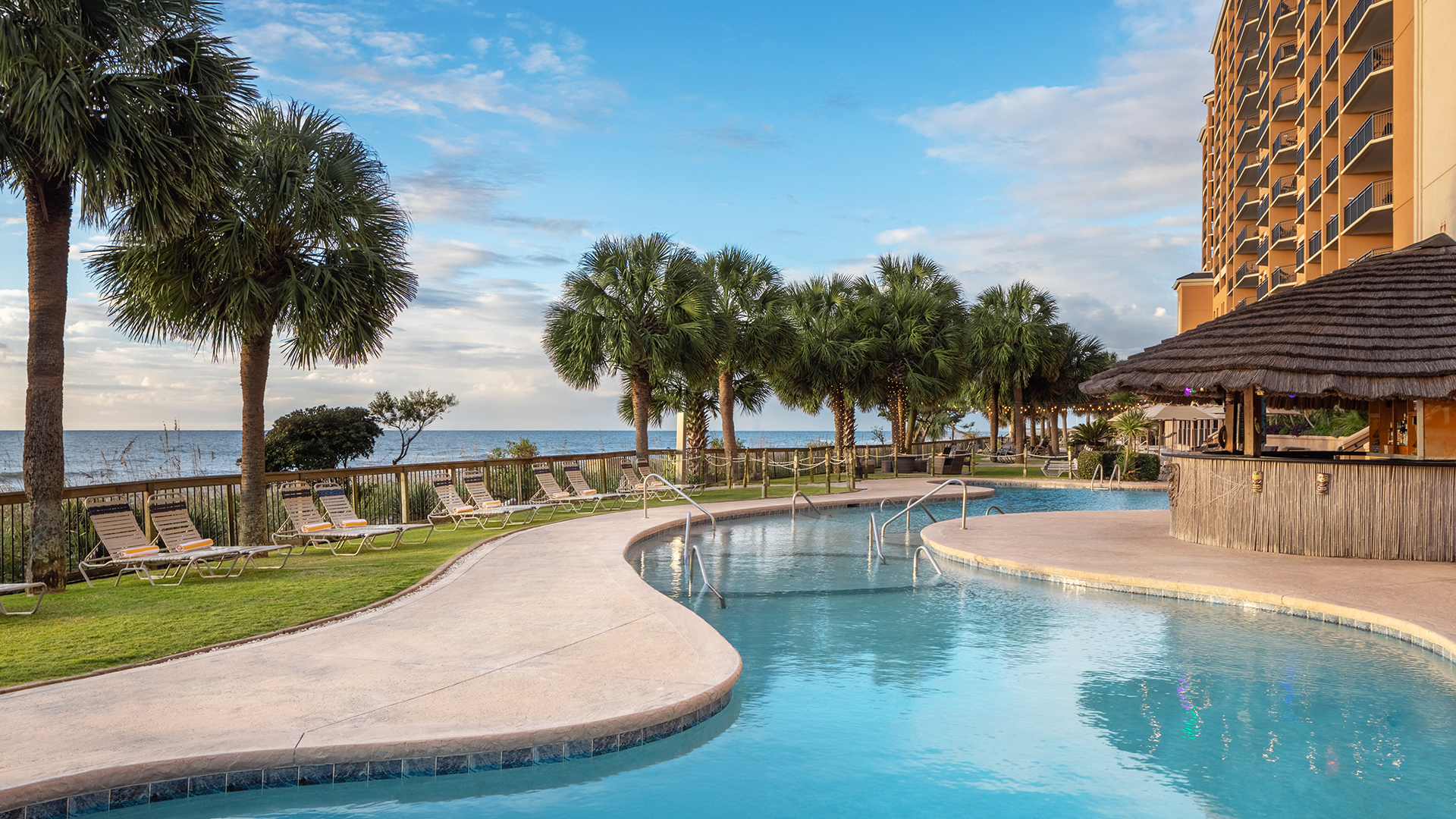 a pool with a walkway and palm trees