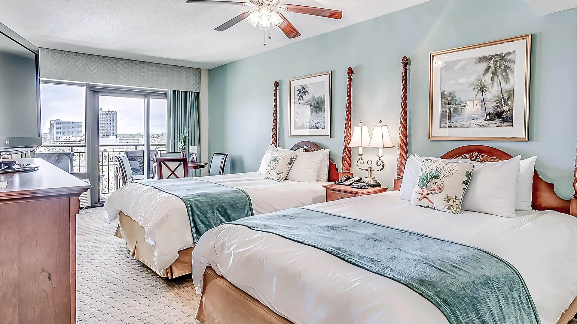 A hotel room with two beds, a balcony, and a television.