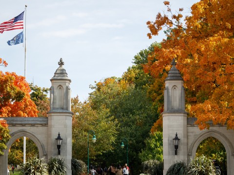 a stone archways with trees and people walking