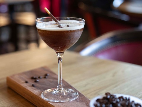 a glass of brown liquid with a straw in it