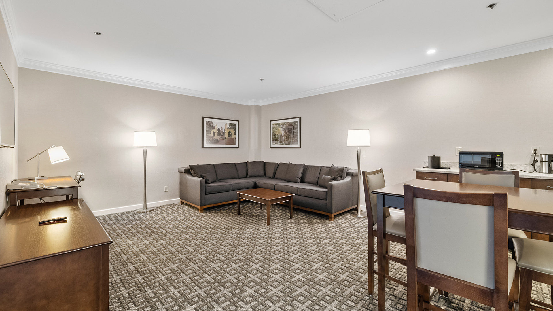 spacious living area with a large grey sectional sofa, coffee table, desk, and dining area