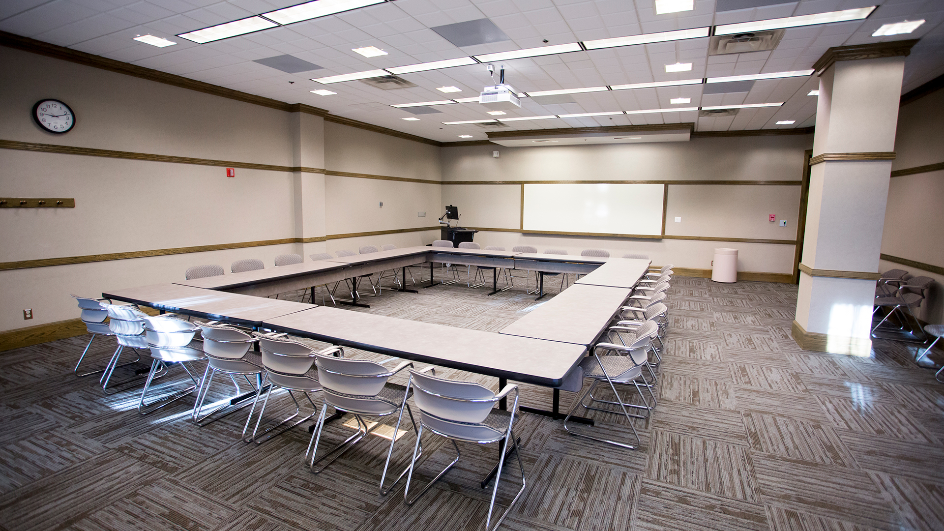 a room with a large square table and chairs