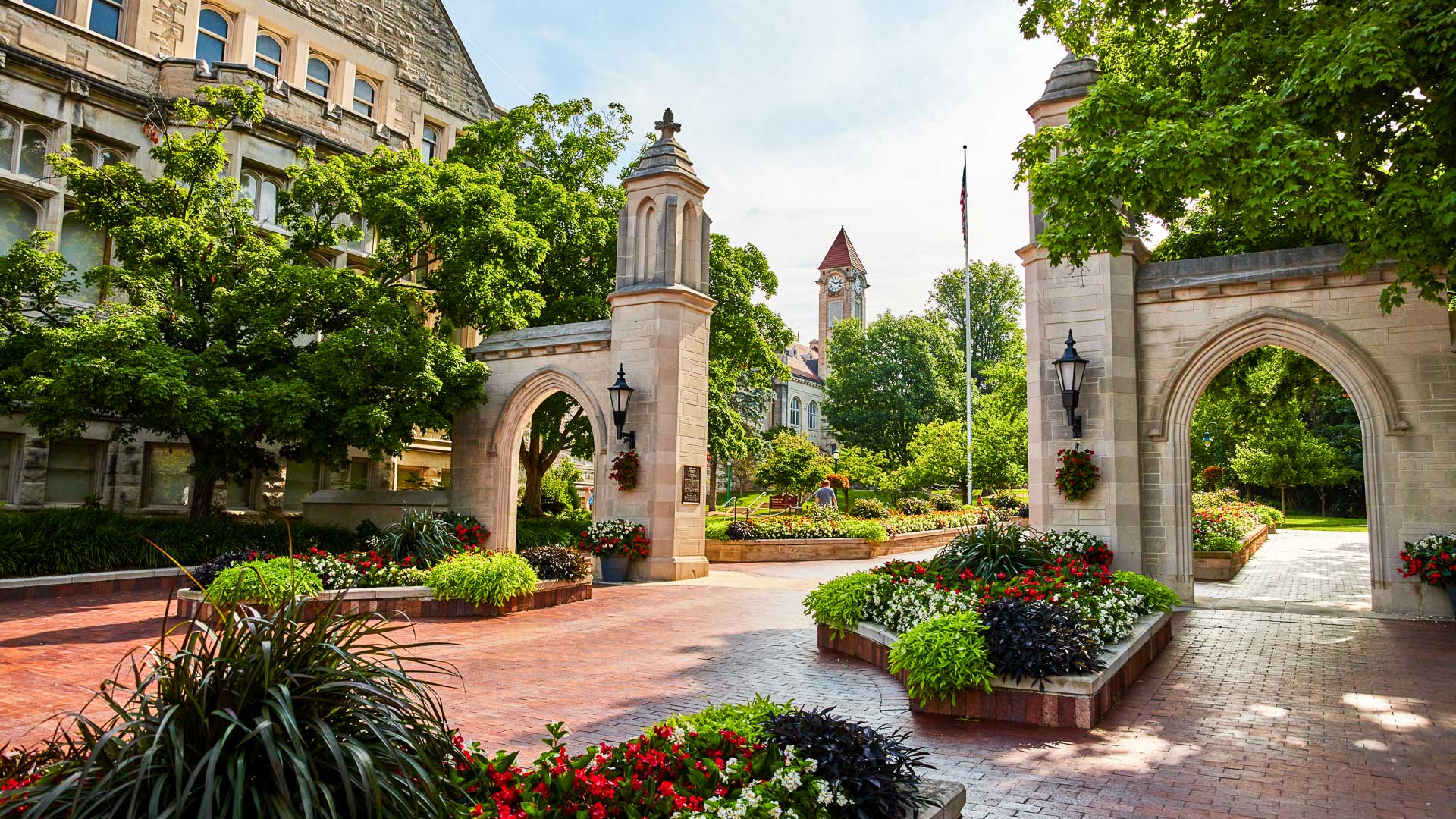 a stone archway with flowers and plants in front of a building
