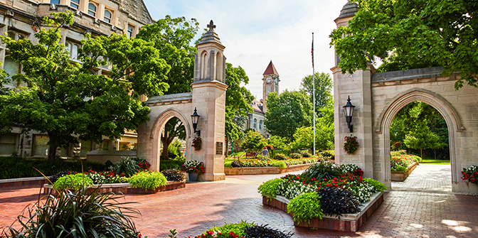 a stone archway with flowers and trees in front of it