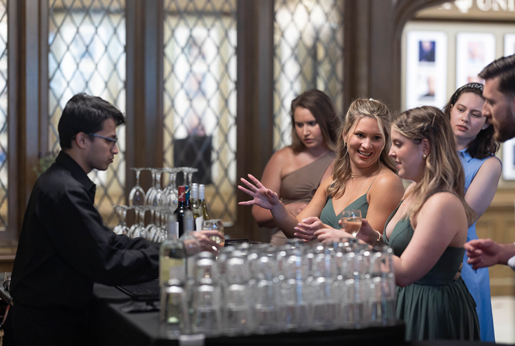 a group of women standing around a table with glasses and bottles
